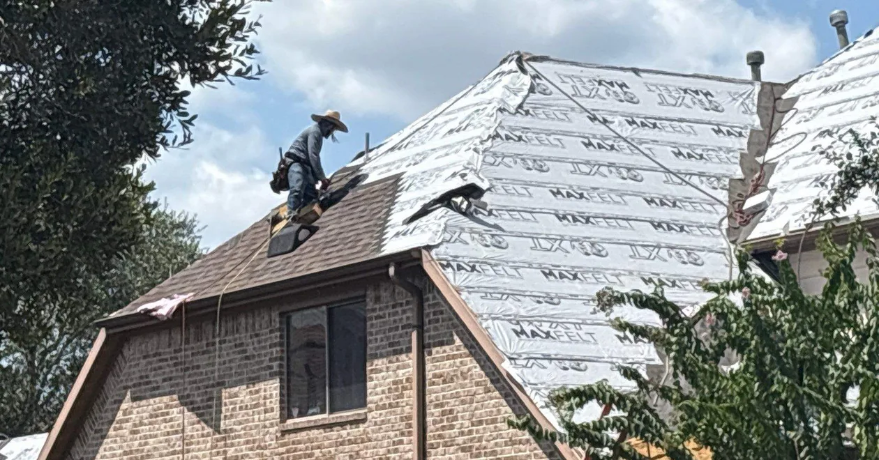 Good Local Roofing crew member working a steep roof over new synthetic underlayment on a brick home.