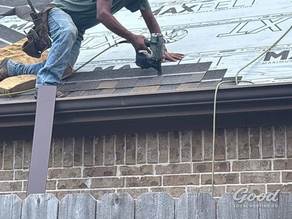 Close view of a roofer fastening shingles along the eave with a nail gun.